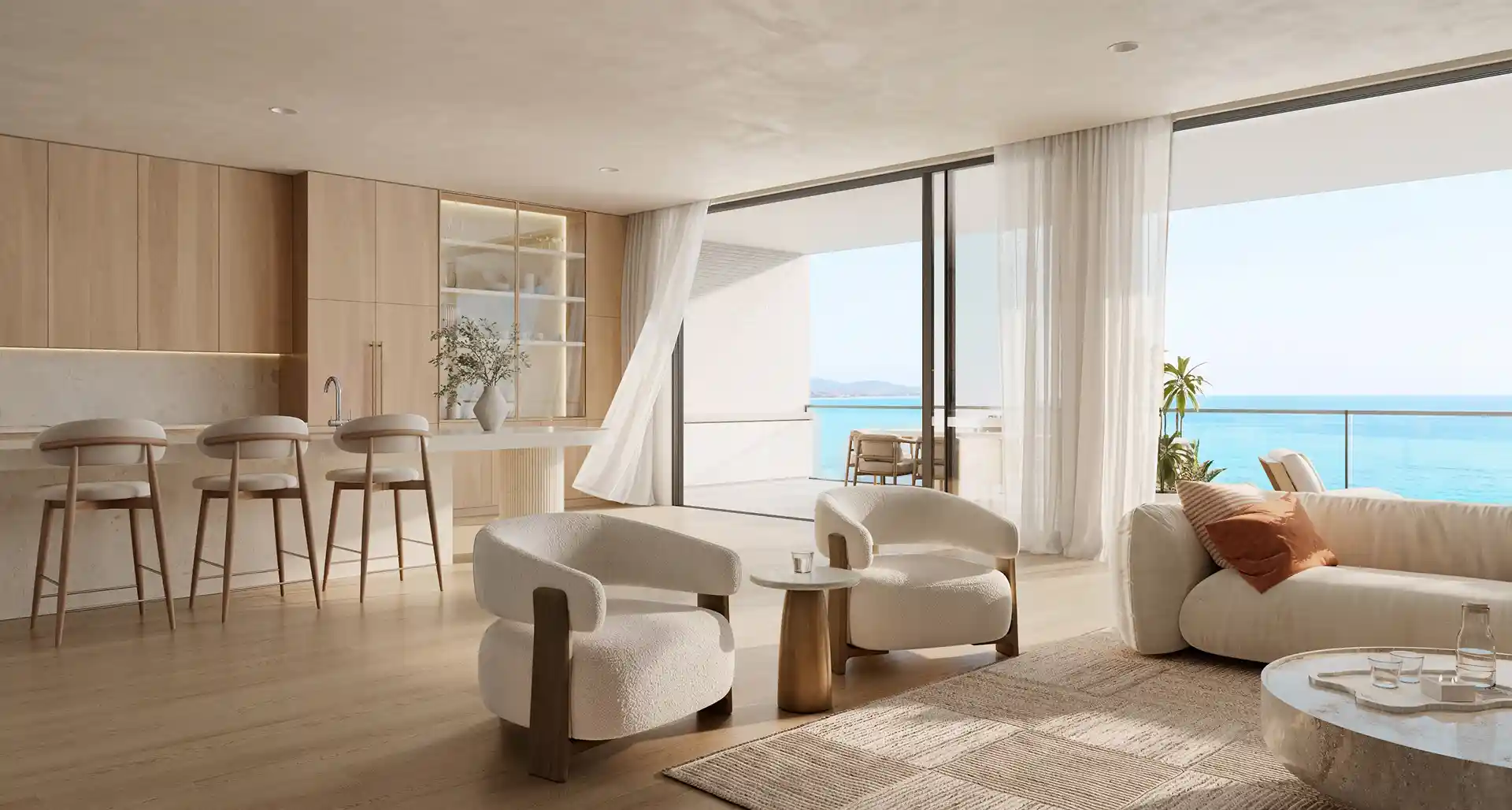 Sala integrada à cozinha, com materiais claros e varanda aberta para o mar.