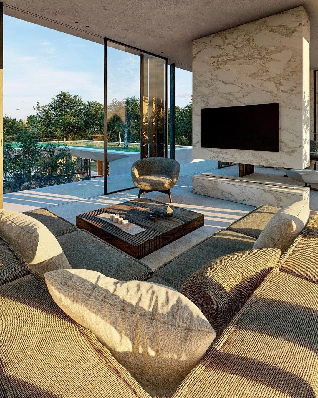 Sala aberta para o jardim, com poltronas, sofá e parede de pedra.